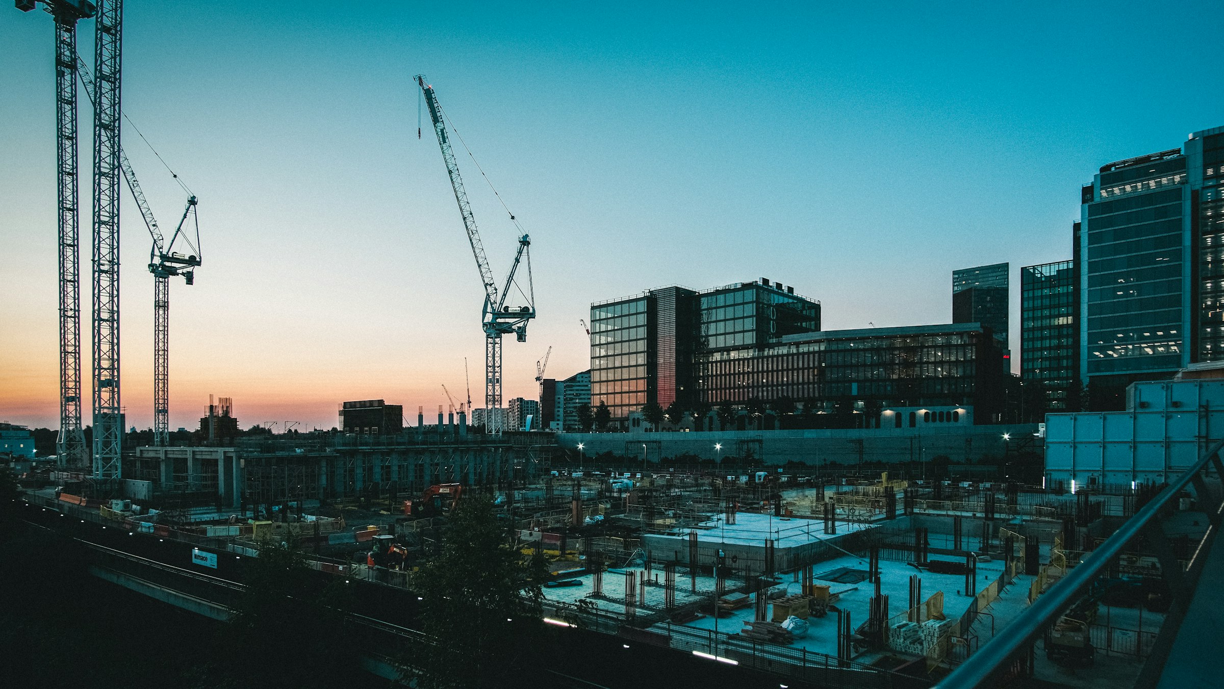 Tower cranes over a construction site at dusk